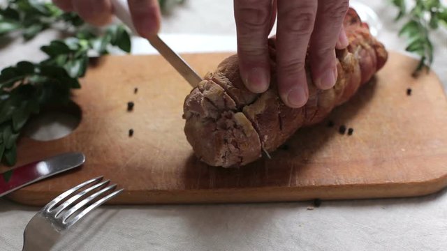 Man is cutting slice of smoked ham