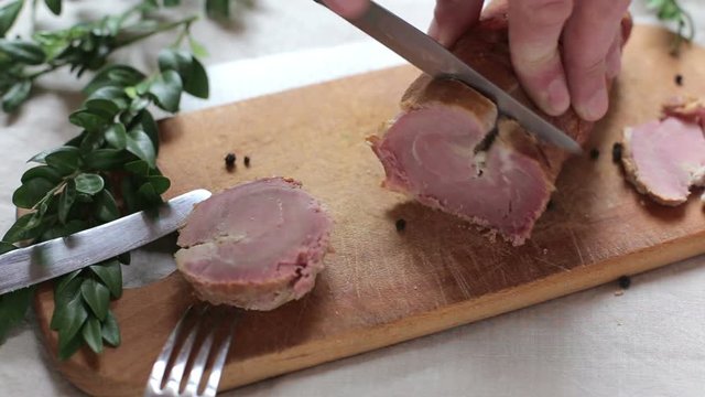 Man is cutting slice of smoked ham