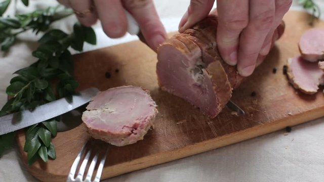 Man is cutting slice of smoked ham