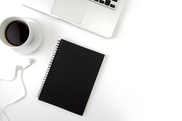 Creative flat lay photo of workspace desk with laptop, earphone, coffee and blank black notebook with copy space background, minimal style