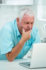 Thoughtful senior man using laptop 