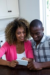 Couple using mobile phone in kitchen