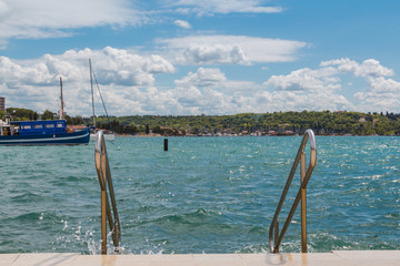 Obraz premium Handrails leading into the sea on a stone embankment of a coastal mediterranean town.