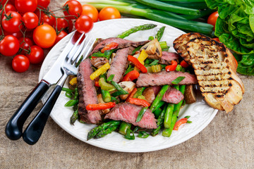 Grilled steak with stir-fried vegetables on plate.