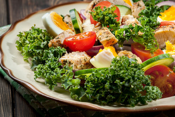 Fresh salad with chicken, tomatoes, eggs and lettuce on plate