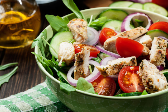 Fresh salad with chicken, tomatoes and arugula on plate