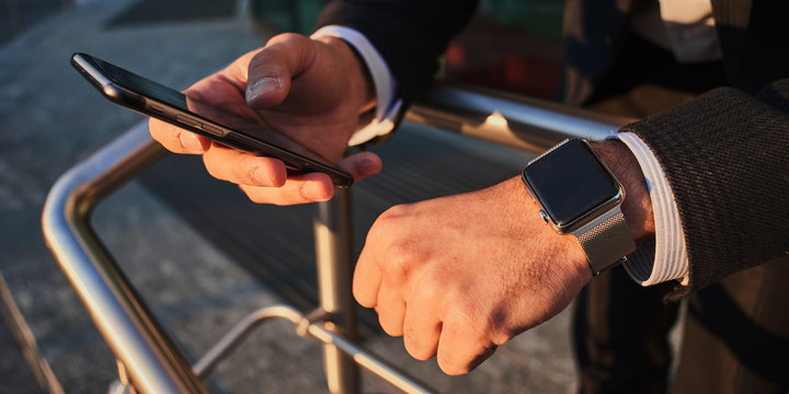 Hand with smart watch and a hand holding the cellphone