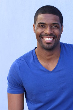 Close up portrait of a laughing african american man posing against blue background