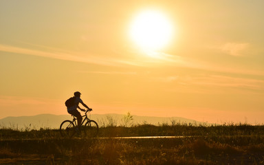 Obraz na płótnie Canvas Cyclist on sunset sky with clouds