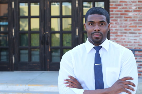 Male High School Teacher Standing By Entrance 