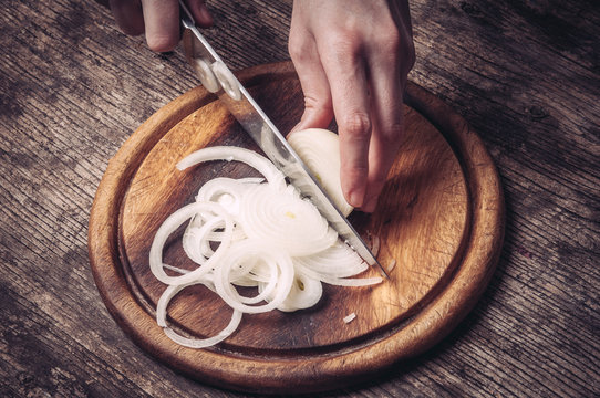 Cutting and chopping onion on wooden board with knife