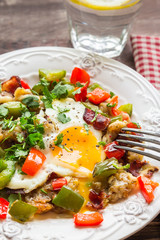 Fried egg with pepper, bacon, potatoes and cilantro
