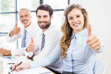 Business colleagues showing thumbs up in a meeting