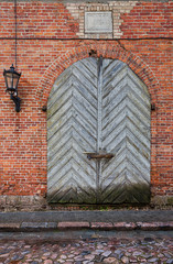 Old rustic wooden door in red brick wall.