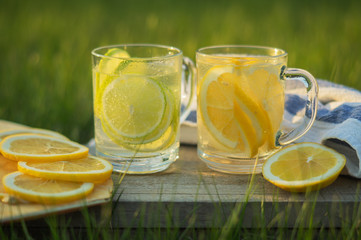 Lemonade with slices of lemon and lime in glass against green blurred background,Life style.
