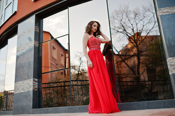 Portrait of fashionable girl at red evening dress posed backgrou