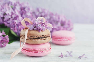 Cup of black coffee, lilac flowers and sweet pastel french macar