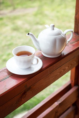 Cup of black tea and kettle on veranda