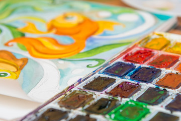 Close-up of watercolors and a fragment of the picture goldfish