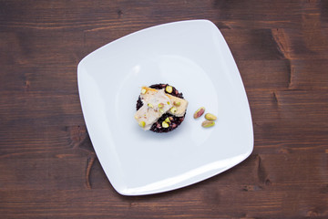 Black rice with fish and pistachios on a wooden table seen from above