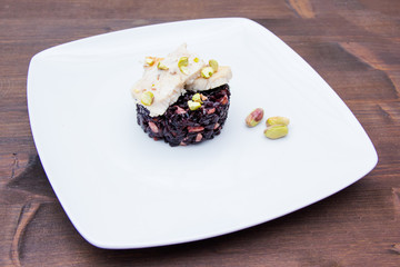 Black rice with fish and pistachios on a wooden table