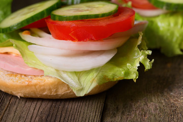 Sandwich with salad and other vegetables on old gray boards