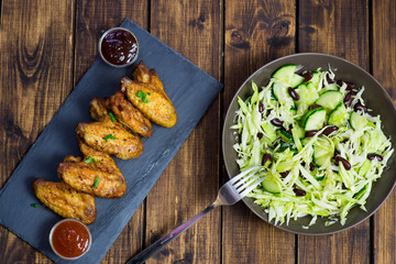 Chicken wings on a slate plate and salad 