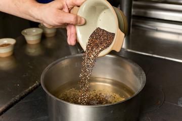 Organic quinoa grain being placed into a pan ready for cooking