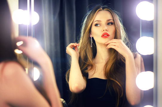 Beautiful sexy young caucasian woman looking into makeup mirror at herself and enjoying her time.