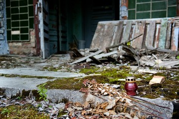 Icon-lamp and bouquet of withered roses lay on stairs, overgrown with moss, at the house entrance...