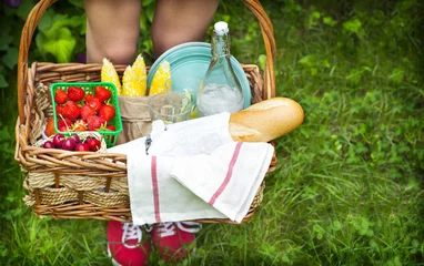 Fotobehang Picknick Young girl holding a picnic basket with berries, lemonade and br