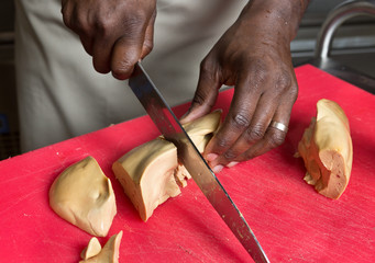 Obraz premium a knife slicing through fresh Foie Gras, on a red cutting board.