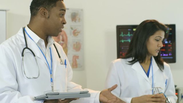 Pan from a mature female patient in the scene to her two doctors speaking to one another.