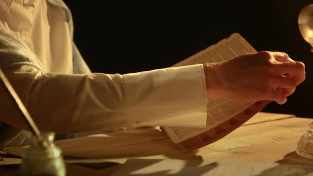 A woman from the era of the early American west reads her Bible by the light from an oil lamp.