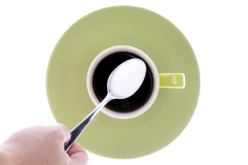 close-up shot of a person holding spoon full of sugar over cup of coffee.