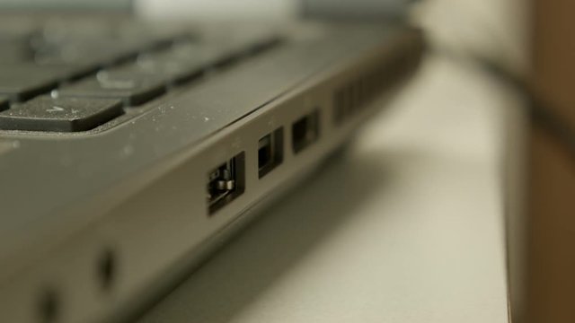 Technician plugging in and unplugging a USB connector to an open port on a laptop computer.