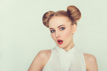 Close-up portrait of surprised beautiful girl with funny hairstyle with open-mouthed. 