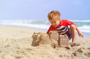 little boy play with sand on summer beach