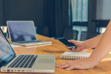 Businesswoman using smartphone and laptop working in office