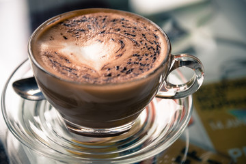 A cup of coffee with heart pattern on wooden background.Toned image.