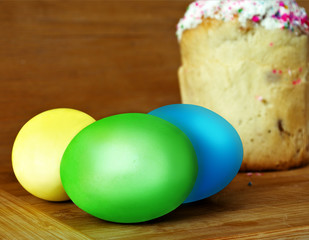 Easter eggs and an Easter cake on a wooden surface.