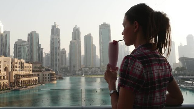 Woman drinking cocktail on the background of skyscrapers in Dubai