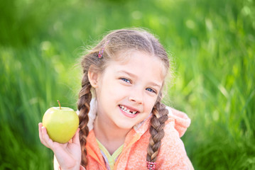 Sweet girl with a fallen toth holding an apple in her hand