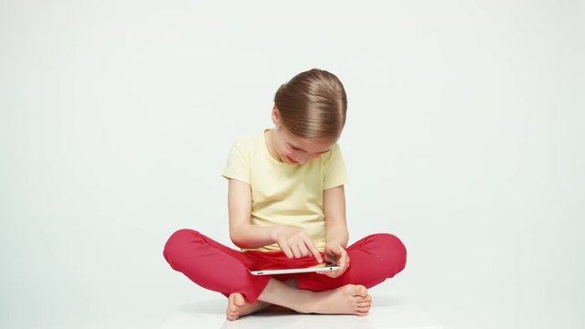 Cute girl 7-8 years old using tablet pc on white background. Thumb up. Ok