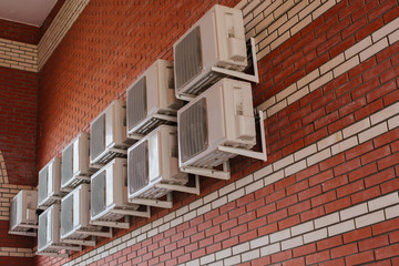 a lot of air conditioners on a brick wall
