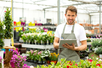 Young attractive man writing notes at the plants nursery