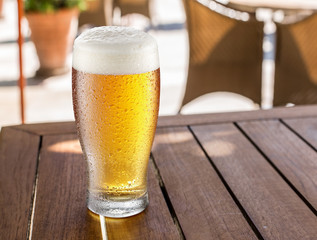 Glass of light beer on the wooden table.