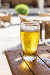 Glass of light beer on the wooden table.