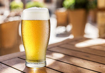 Glass of light beer on the wooden table.