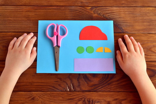 Paper car and parts, scissors. Child put his hands on the wooden table. Kids art. Kids crafts. Child does a greeting card father's day